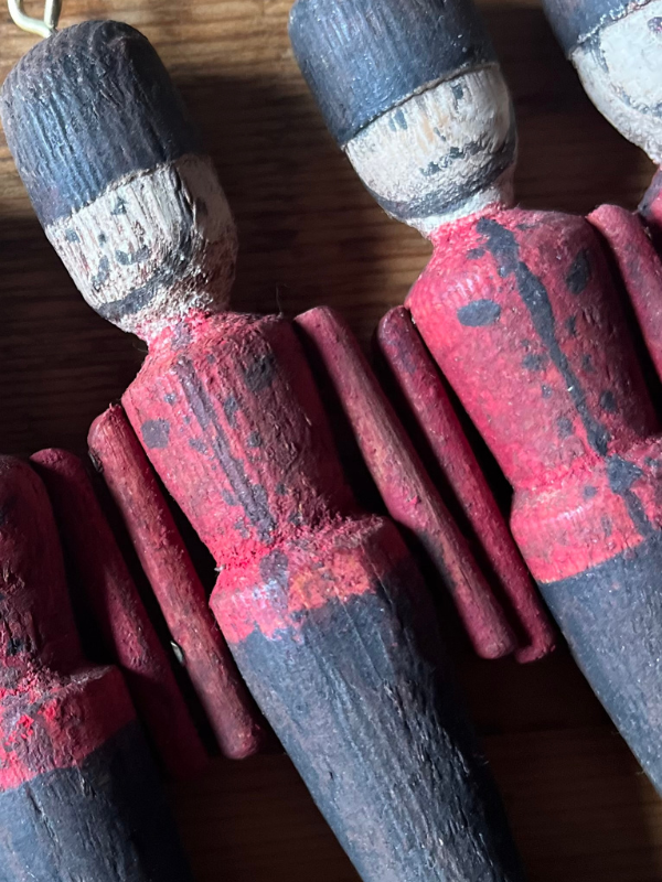 Close up of vintage wooden toy soldiers. Hand painted with red & black uniforms laying flat on a wooden table