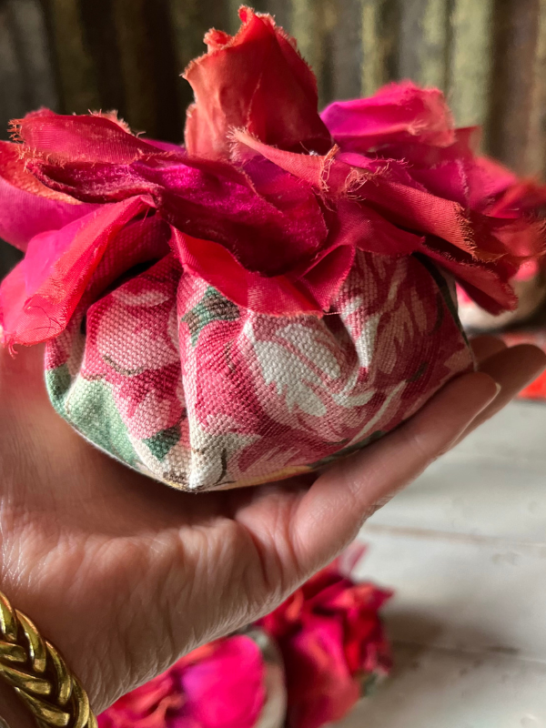 Shot of a hand holding a large handmade vintage lavender flowers with red fabric corsage.