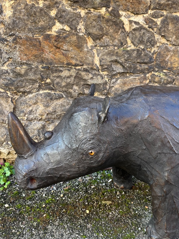 Close up face shot of antique brown leather Liberty style rhino against a brick wall