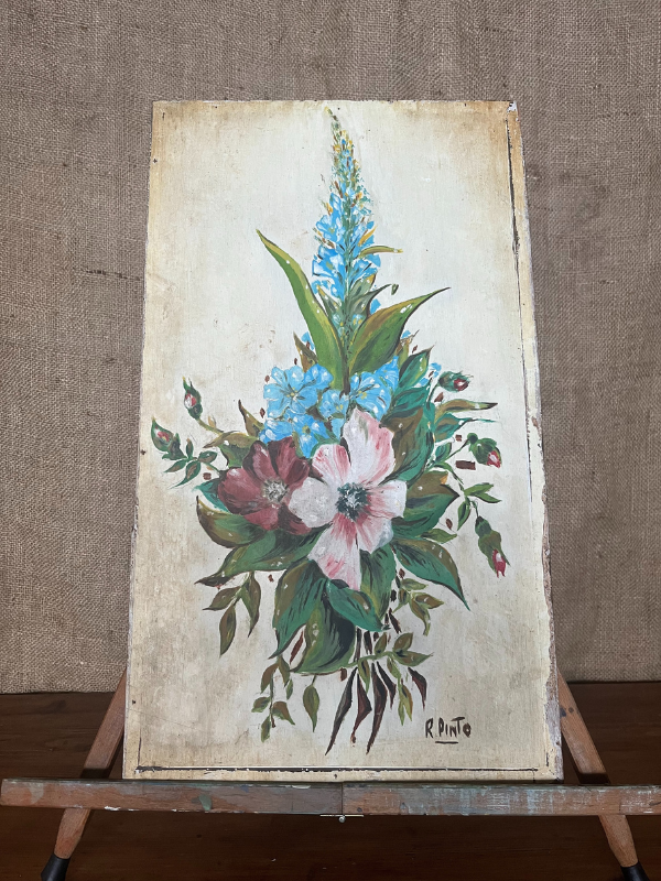 Close view of a small floral painting on white wooden board sitting on a wooden easel