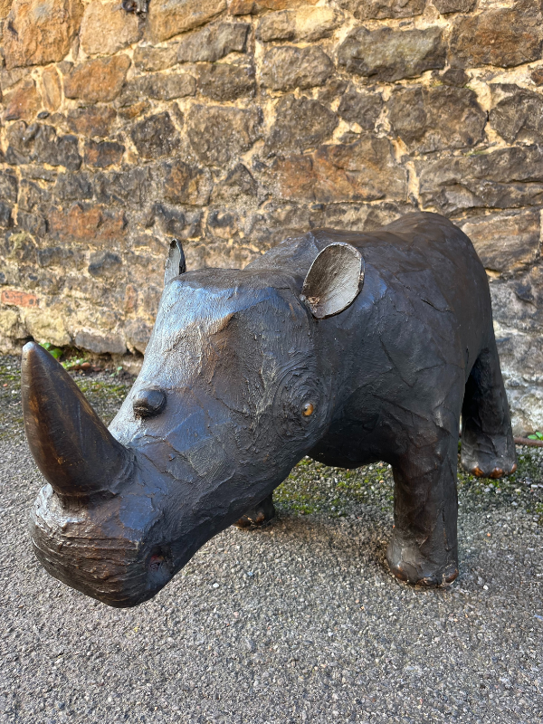 Front view of antique brown leather Liberty style rhino against a brick wall