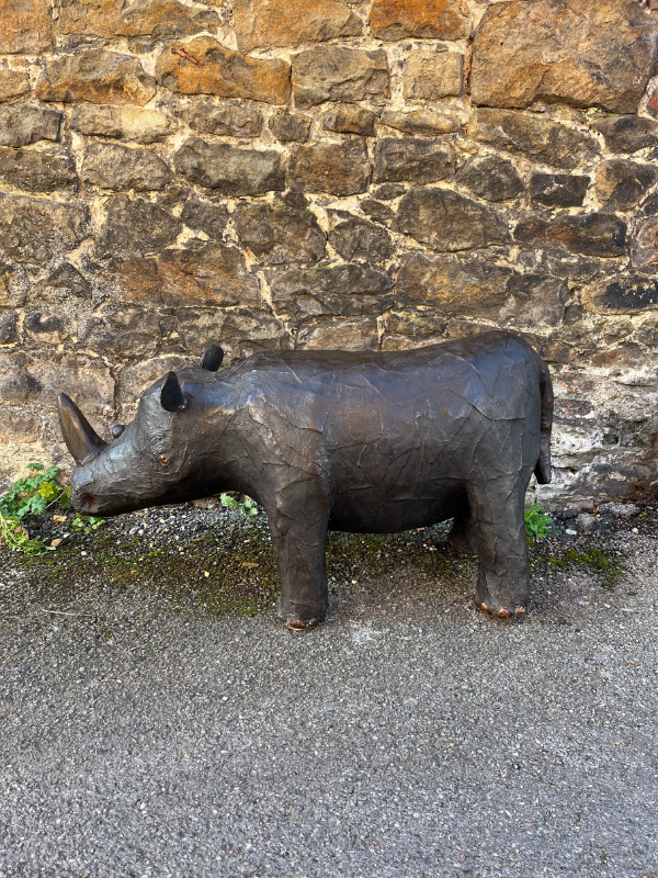Left side of antique brown leather Liberty style rhino against a brick wall