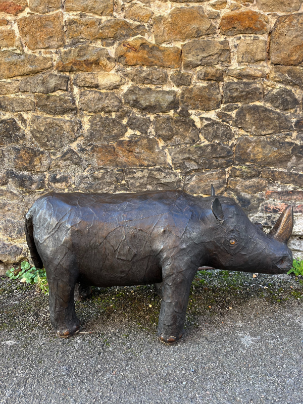 Right side of antique brown leather Liberty style rhino against a brick wall