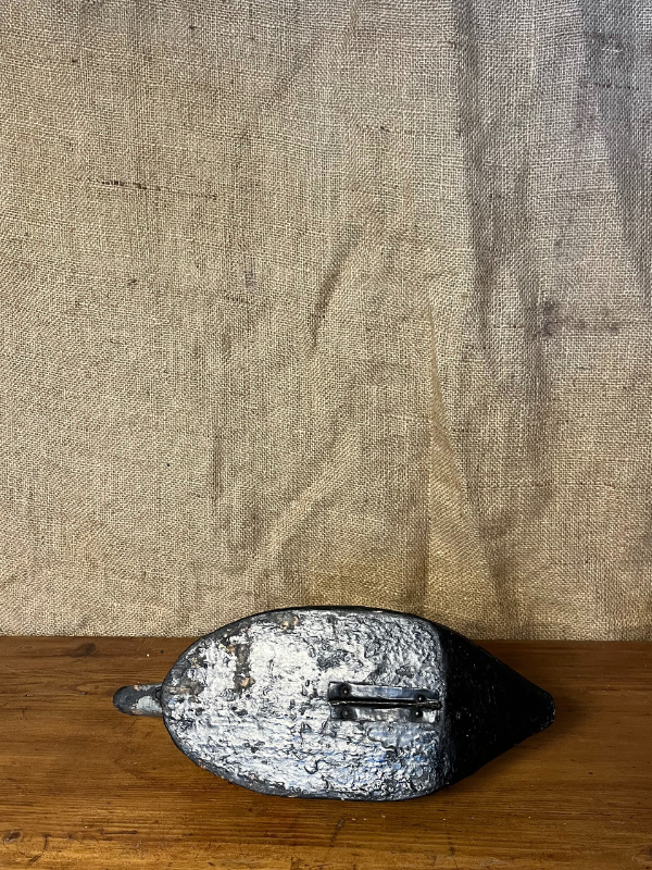 Underside of an antique wooden decoy duck on a pine table