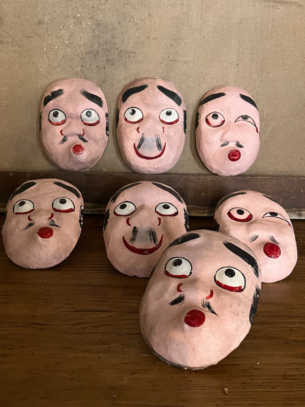 Group of Japanese theatre masks against a canvas backdrop