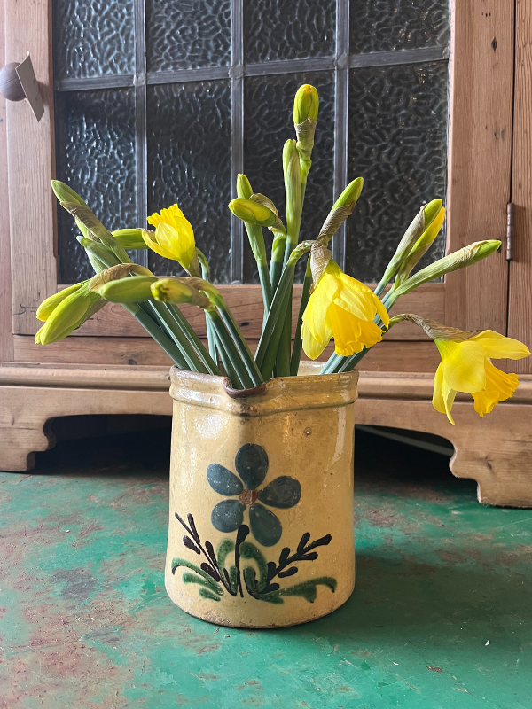 Handpainted small glazed jug with blue painted flower on the front & filled with daffodils