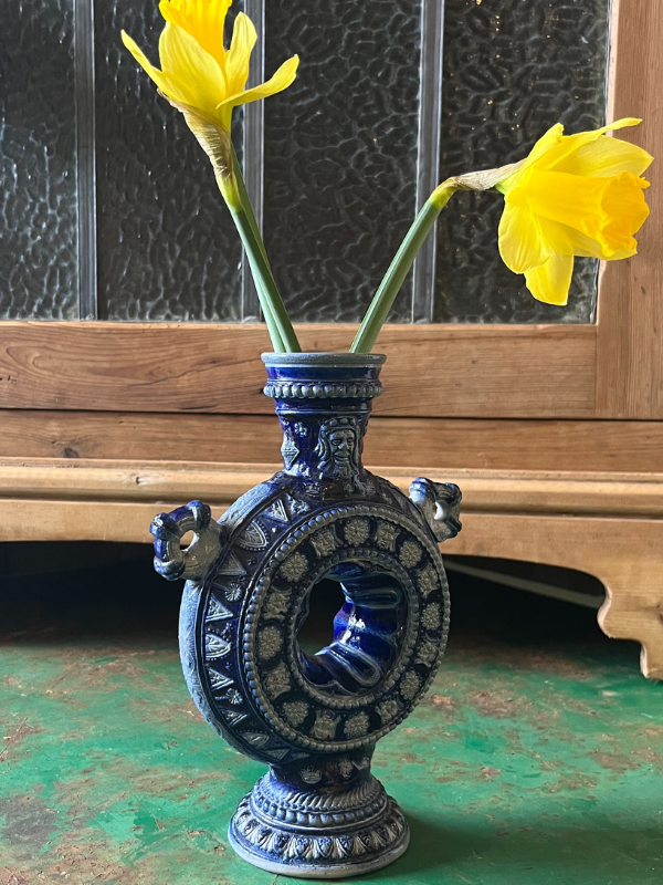 Side view of a blue & white tulipiere vase on a green metal table
