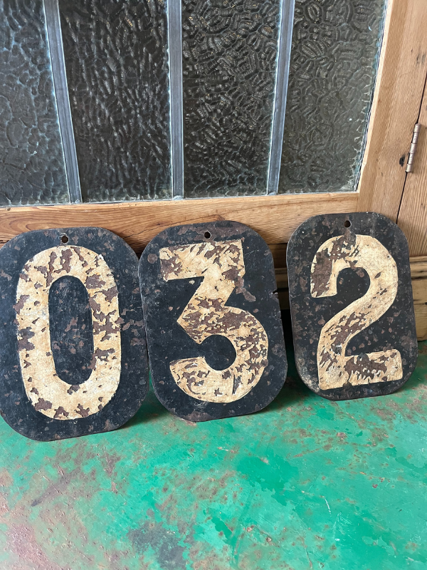 Black & white vintage metal numbers 032 propped up against a wooden cupboard