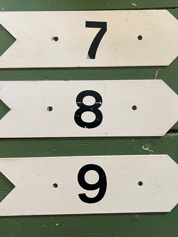Vintage golf numbers 7 8 9 on a green wooden floor