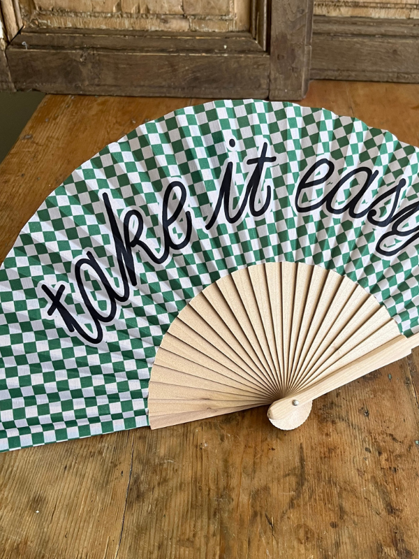 Close view of Take it Easy green gingham fan on wooden table