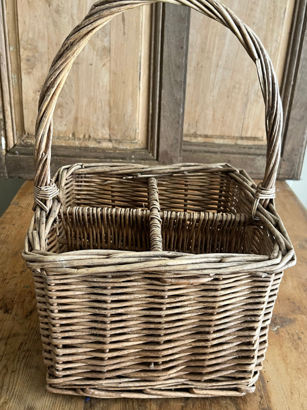 Close view of a vintage wicker bottle basket on a wooden table
