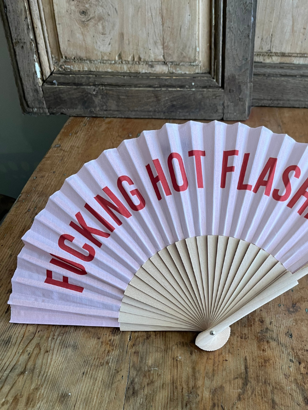 Lettering detail of F.ing Hot Flashes fan on wooden table