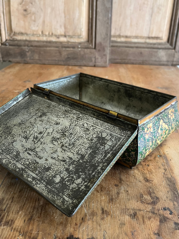 Open highly decorated vintage tin on a wooden table