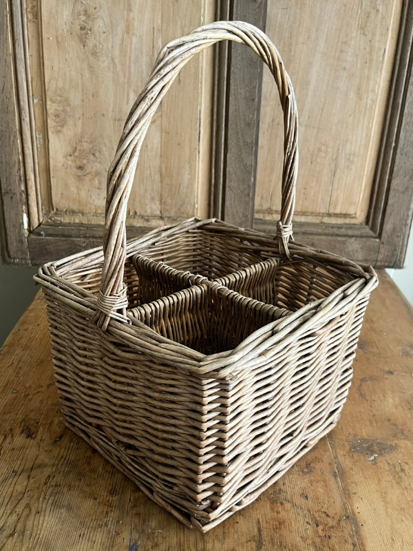 Side view of a vintage wicker bottle basket on a wooden table