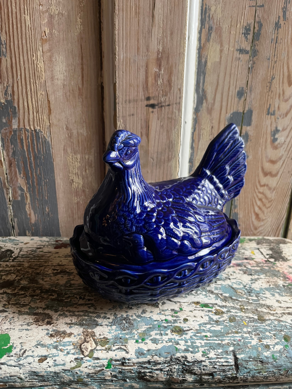Blue ceramic chicken egg holder against a wooden background
