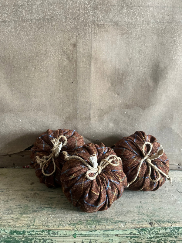Group-of-handmade-brown-woollen-pumpkins-against-an-old-faded-canvas-background