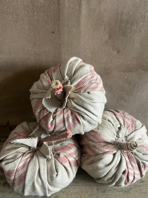 Group of handmade pumpkins in beige ticking fabric against a neutral canvas background