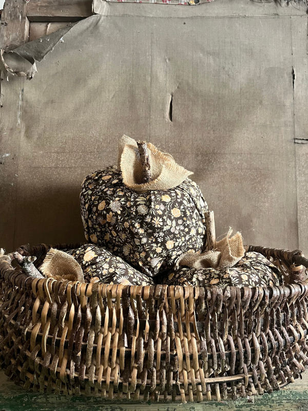Large brown floral fabric pumpkins in a wicker basket against canvas background