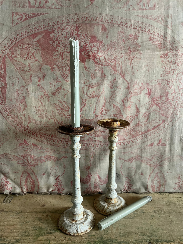 Pair of grey candlesticks against pink toile de jouy fabric