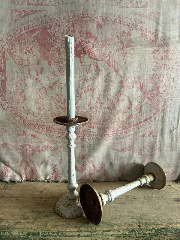 Pair of grey cast iron candlesticks one laying to show underside.png