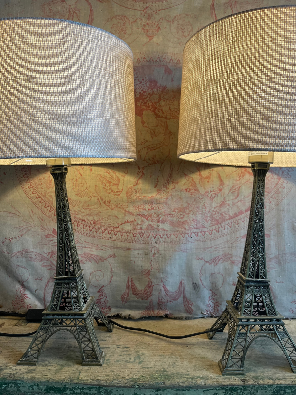 Pair of lit up Eiffel Tower lamps against pink toile de jouy fabric