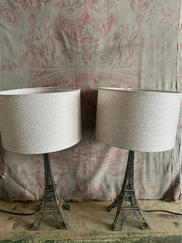 Pair of unlit Eiffel Tower lamps against pink toile de jouy fabric
