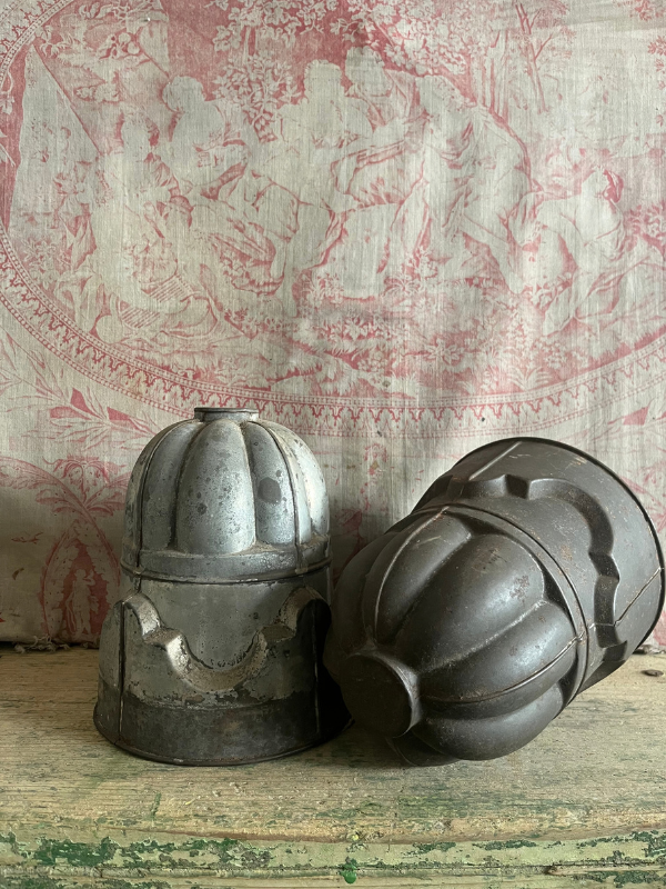 Pair of vintage detailed metal jelly moulds against pink toile de jouy fabric