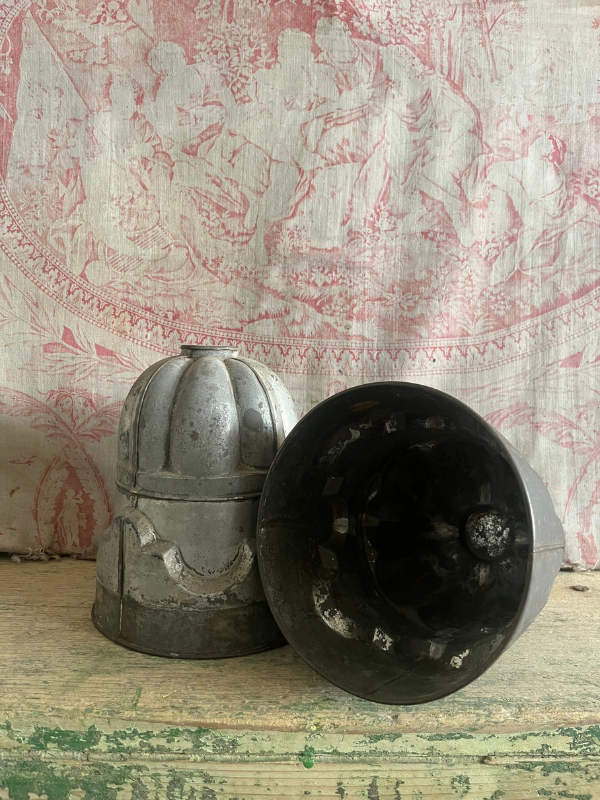 Showing the underside of a vintage detailed metal jelly mould on a green wooden bench