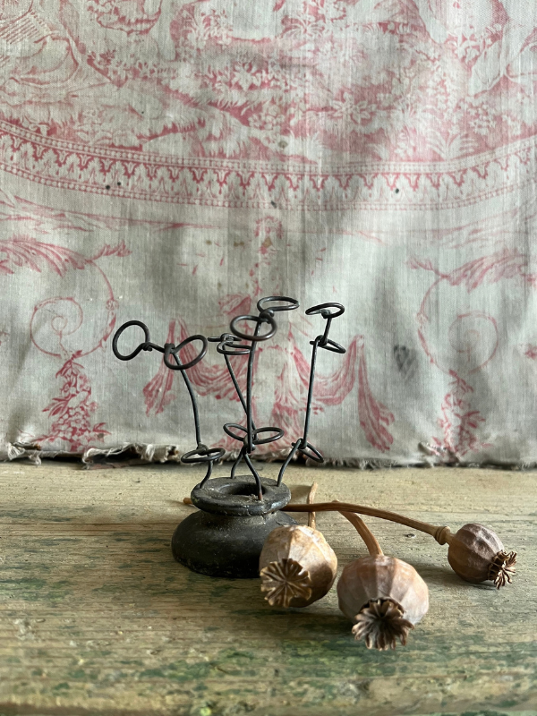 Vintage metal FloralAid flower holder against pink toile de jouy fabric with dried poppy seed heads