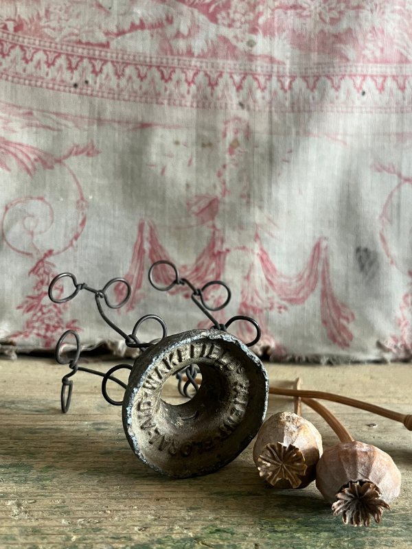 Underside of a vintage metal FloralAid flower holder showing Wakefield makers stamp
